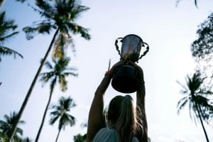 image of woman holding up trophy for blog post "what is indemnity insurance"